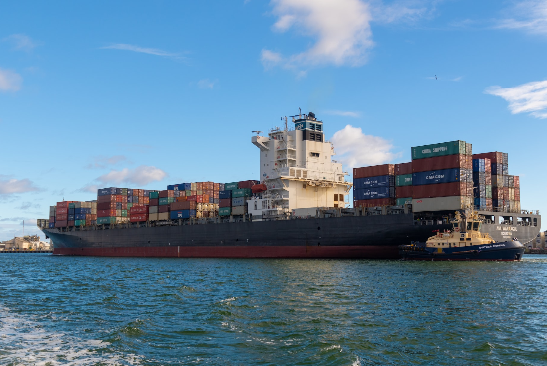 black cargo ship on sea under blue sky during daytime